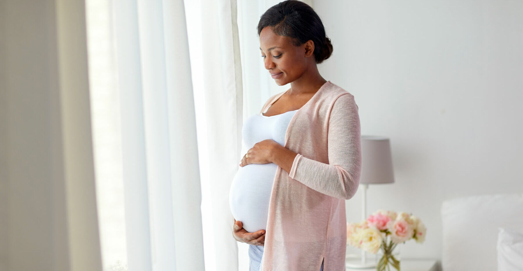 pregnant african american woman at home window